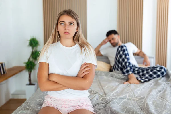Frustrated sad girlfriend sit on bed think of relationship problems, thoughtful couple after quarrel lost in thoughts, upset lovers consider break up, offended person disappointed by boyfriend