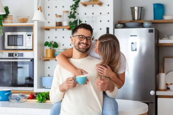 Romantic couple in love spending time together in kitchen. Cute young couple drinking coffee in kitchen and enjoying morning time together