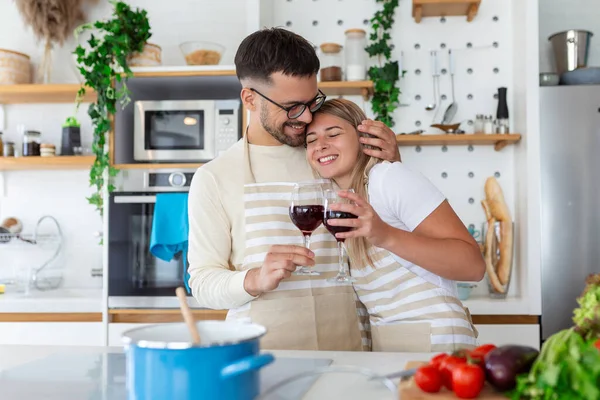 Romantic young couple cooking together in the kitchen,having a great time together. Man and woman laughing and drinking wine
