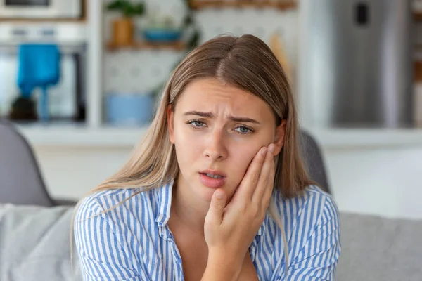 Portrait of unhappy woman suffering from toothache at home. Healthcare, dental health and problem concept. Stock photo