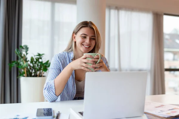 Beautiful woman freelancer noting information for planning project doing remote job via laptop computer. woman laughing while reading email on modern laptop device .