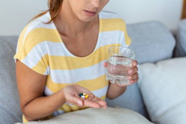 Kadın bir bardak suyla ilaç alıyor. Günlük vitamin normu, etkili ilaçlar, vücut ve ruh sağlığı konsepti için modern eczane
