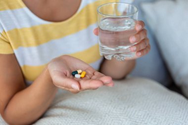Kadın bir bardak suyla ilaç alıyor. Günlük vitamin normu, etkili ilaçlar, vücut ve ruh sağlığı konsepti için modern eczane