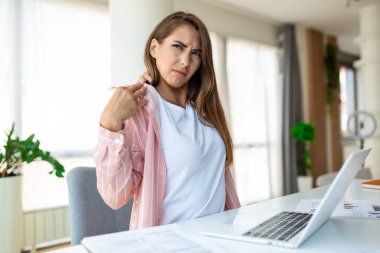 Genç stresli bir kadının portresi, dizüstü bilgisayarın önünde oturmuş, omuza dokunarak acı çeken, dizüstü bilgisayarla çalıştıktan sonra omuz ağrısı çeken bir kadın.