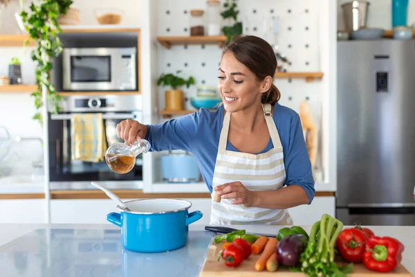 自宅のモダンなキッチンに立つ鍋で幸せな若い女性の料理の試飲ディナー 健康食品の笑顔を準備主婦 家庭と栄養 ダイエットレシピコンセプト — ストック写真