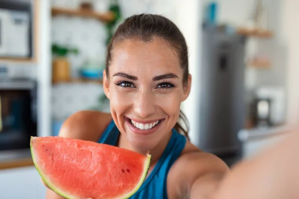Young woman eats a slice of watermelon in the kitchen. Portrait of young woman enjoying a watermelon.