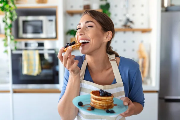 台所でパンケーキを作る若い女性 朝食にブルーベリーパンケーキを楽しむ若い主婦 — ストック写真