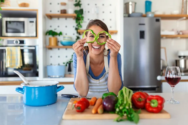 Foto Mujer Joven Sonriendo Con Rodajas Pimiento Verde Mientras Cocina —  Fotos de Stock