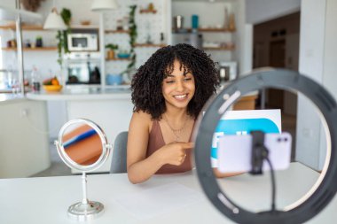 Genç bir kadın etkileyicisi akıllı telefonunu bir video bloğu yazısında kullanıyor..