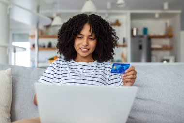 Güzel bir kadın kredi kartıyla online alışveriş yapıyor. Kredi kartı tutan ve laptop kullanan bir kadın. Çevrimiçi alışveriş kavramı
