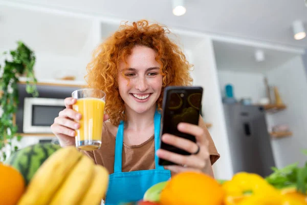 Mujer Bonita Sonriente Mirando Teléfono Móvil Sosteniendo Vaso Jugo Naranja — Foto de Stock