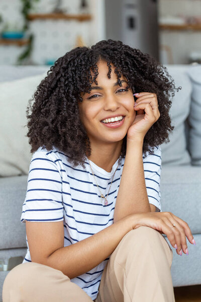 Portrait of a beautiful woman smiling at home. African woman in casual looking at camera with copy space. Cheerful mixed race girl relaxing at home