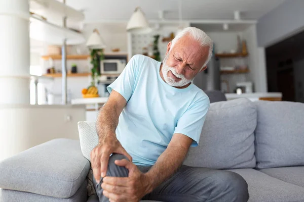Oudere Man Zit Thuis Bank Heeft Pijn Het Kniegewricht Houdt — Stockfoto