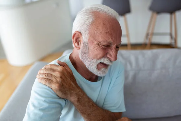 Senior elderly man touching his shoulder, suffering from shoulder pain, sciatica, sedentary lifestyle concept. shoulder health problems. Healthcare, insurance