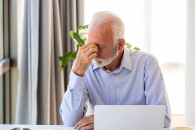 Dizüstü bilgisayarı olan stresli bir iş adamı. Başı da ağrıyabilir. O, toplantı odasında oturuyor. Masada belgeler ve dizüstü bilgisayarlar var. Boşluğu kopyala