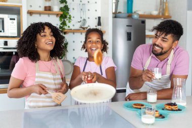 Evdeki mutfakta krep hazırlayan aile, ailesine krep pişirmede yardım eden çalışkan genç kız. Fotoğrafı kapat