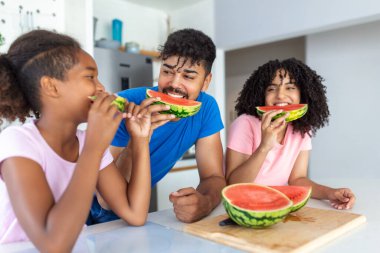 Neşeli baba ve küçük kızının karpuz yerken mutlu göründükleri yakın çekim..