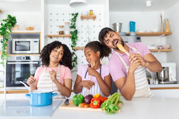 自宅で昼食を調理しながら楽しいアフリカ系アメリカ人の家族 マイクとしてSpatulasを使用して娘と陽気な家族 フリースペース — ストック写真