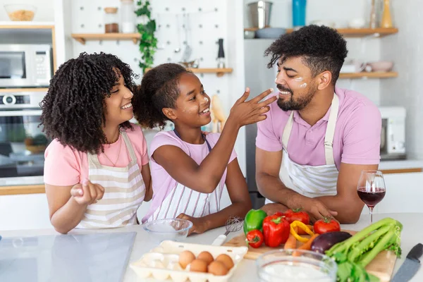 かわいい女の子と彼女の美しい両親は 自宅でキッチンで料理をしながら笑っています キッチンで一緒に健康的な食べ物を準備する幸せなアフリカ系アメリカ人の家族 — ストック写真