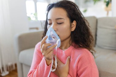 Sick Asian woman making inhalation, medicine is the best medicine. Ill woman wearing an oxygen mask and undergoing treatment for covid-19. woman with an inhaler