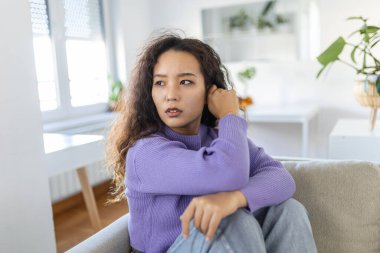 İşle ya da ilişkilerle ilgili sorunları olan üzgün bir kadın, koltukta oturuyor, yüzü örtülü, umutsuzluk ve endişe hissediyor, yalnızlık çekiyor, psikolojik sorunlar yaşıyor.