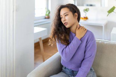 Asian woman suffering from backache at home. Lower Back Pain . Woman feels back pain massaging aching muscles, sad woman suffers from low-back