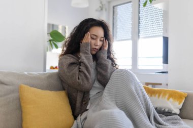 Sinus ache causing very paintful headache. Unhealthy Asian woman in pain. Sharp strong sore. Sinus pain, sinus pressure, sinusitis. Sad woman holding her head because sinus pain