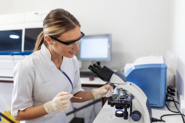 Scientist biochemist or microbiologist working research with a microscope in laboratory.