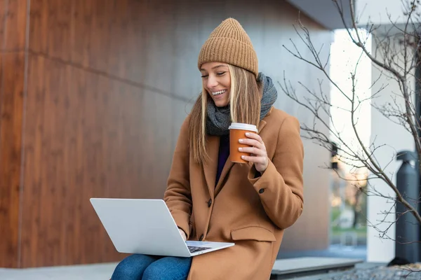 Young Woman Wide Smile Sitting Bench Looks Laptop Coffee Her — Stok fotoğraf