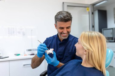 Dentist showing dental plaster mold to the patient. Dentist doctor showing jaw model at dental clinic, dental care concept. Dental care concept. clipart