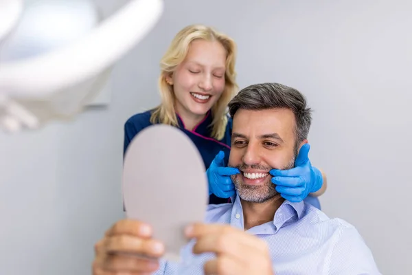 Bonito Homem Sorrindo Enquanto Olha Para Espelho Clínica Dentária Tiro — Fotografia de Stock