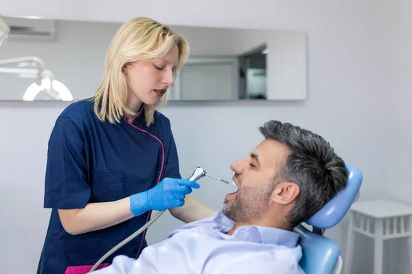 歯医者は歯医者の所で患者の歯を調べる 歯医者の診療所で歯科治療を受けた患者 — ストック写真