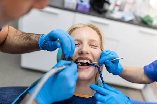 Close-up of a dental drill procedure at dentist approaching a patient with dental instruments held in the hands protected with surgical gloves