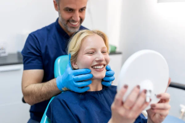 Mujer Joven Europea Sonriendo Mientras Mira Espejo Clínica Dental Fotografía — Foto de Stock