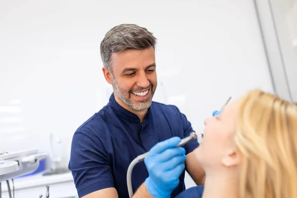 歯医者の診察中に若い女性とコミュニケーションをとりながら歯を確認する笑顔 — ストック写真