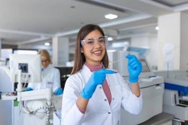 Laboratuvardaki mikroskobun yanındaki genç bilim adamının elindeki petri kabı. Mikrobiyoloji laboratuvarında çalışan bir kadın araştırmacı tarafından bakteri kültürü levhası incelemesi