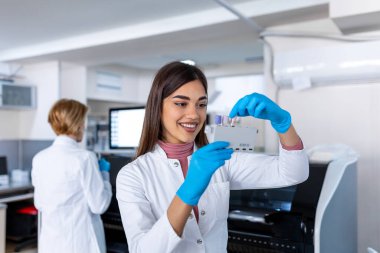 Laboratory assistant putting test tubes into the holder. Scientist doctor looking at blood test tube working at biochemistry experiment in microbiology hospital laboratory.