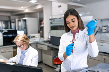Modern Tıbbi Araştırma Laboratuvarı: Mikro Pipette ile çalışan kadın bilim adamı, Test Örnek Analizi için Dijital Tablet kullanılıyor. Gelişmiş Tıp, Biyoteknoloji Geliştirme Laboratuvarı.