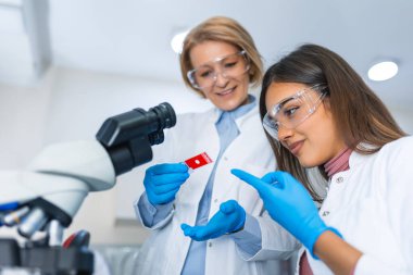 Laboratuvarda araştırma yapan ve laboratuvar makineleri, slaytlar, mikroskop ve tüm laboratuvar ekipmanları kullanan bilim adamları.