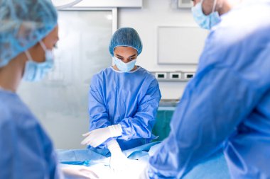 Profesyonel Cerrah, Asistanlar ve Hemşireler Ekibi Hastane Ameliyathanesinde Bir Hastaya İstilacı Ameliyat Yapıyor. Cerrahlar konuşur ve aletleri kullanır. Gerçek Modern Hastane.