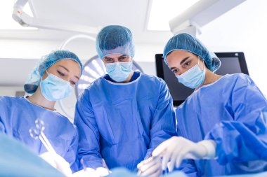 Bir grup tıbbi ekip acilen cerrahi operasyon yapacak ve hastanedeki hastalara yardım edecek. Tıbbi ekip, modern bir ameliyathanede cerrahi operasyon gerçekleştiriyor.