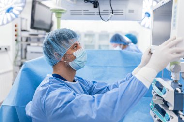Anestezi uzmanı kalp ameliyatı sırasında vücudun hayati fonksiyonlarını takip ediyor. Cerrah ameliyat sırasında tıbbi monitöre bakıyor. Doktor hasta sağlığı durumunu kontrol ediyor..