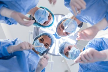 Surgeons standing above of the patient before surgery. Multi-ethnic healthcare workers performing surgery on patient at operation theater.