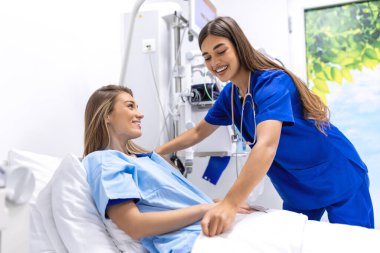 Yatakta genç bir hasta hastane odasında kadın doktorla, sağlık ve sigorta konseptiyle konuşuyor. Hastayı hastane yatağında teselli eden ya da sağlık hizmeti veren bir doktor..