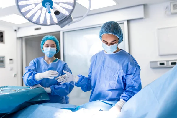 실에서 손으로 수술중에 의사들에게 악기를 내보낸다 외과의는 작전을 의사들이 수술을 — 스톡 사진