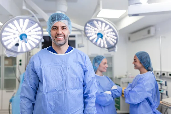 男外科医生双臂叉腰站立在医院手术室的画像 在一个现代化的手术室里 队医在做手术 中年医生在看相机 — 图库照片