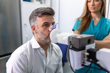 Yetişkin adam sprometri ile nefes alma fonksiyonlarını test ediyor. Sağlık sorunları var. Akciğer hastalığında solunum fonksiyonu teşhisi.