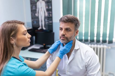 Terapist sisteminde profesyonel danışmanlık kavramı. Tıp bürosunda erkek bademciklerini muayene eden doktor kadının yakın portresi.