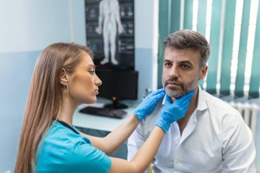 Terapist sisteminde profesyonel danışmanlık kavramı. Tıp bürosunda erkek bademciklerini muayene eden doktor kadının yakın portresi.