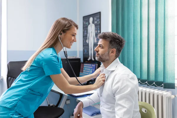 Den Unge Läkaren Använder Ett Stetoskop Och Lyssnar Patientens Hjärtslag — Stockfoto